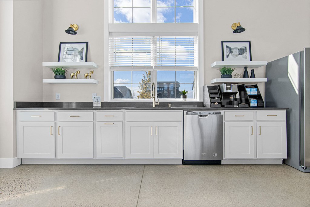 a kitchen with white cabinets and a large window