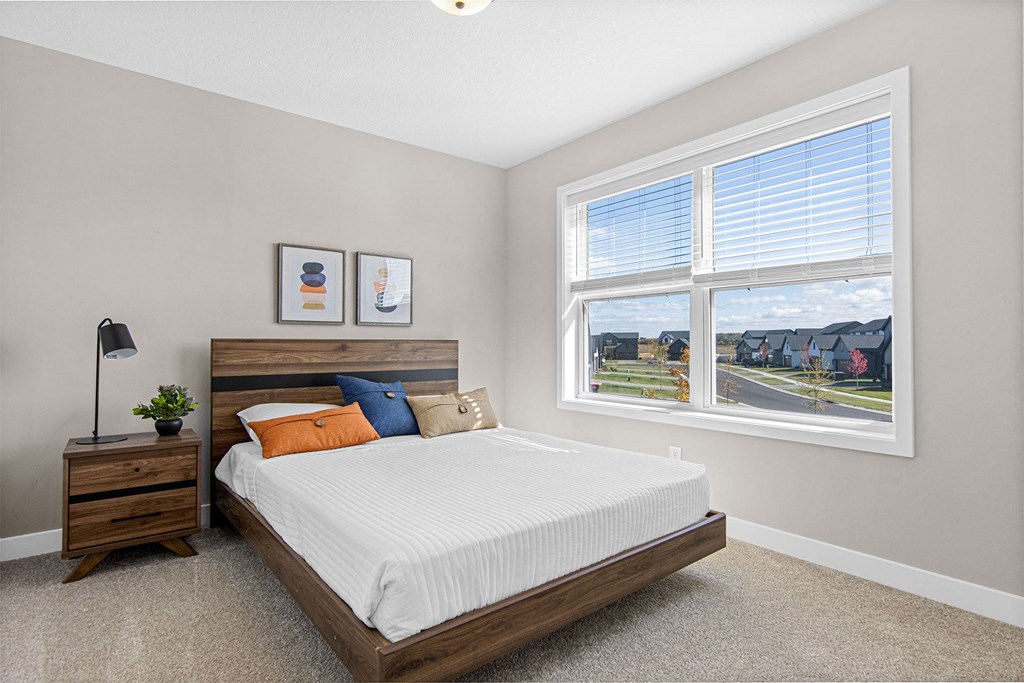 a bedroom with a large window and a bed with a wooden headboard