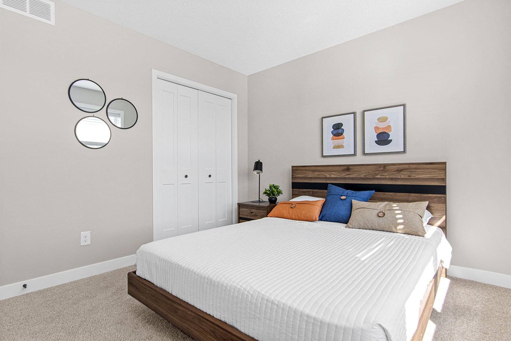 a bedroom with a white bed and two mirrors on the wall