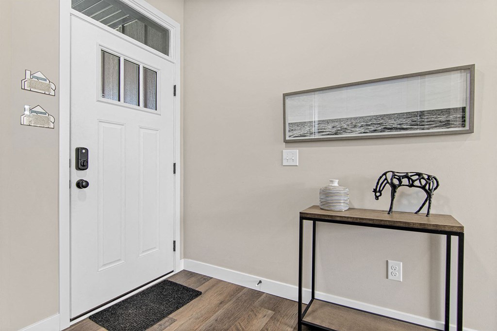 a entryway with a white door and a table with a vase on it
