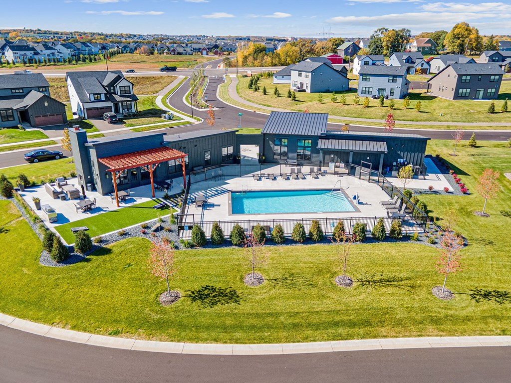 an aerial view of a large pool in a grassy area with houses in the background