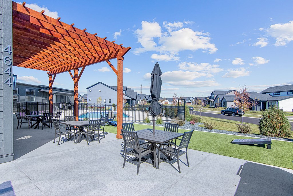 a patio with a pergola and tables with umbrellas