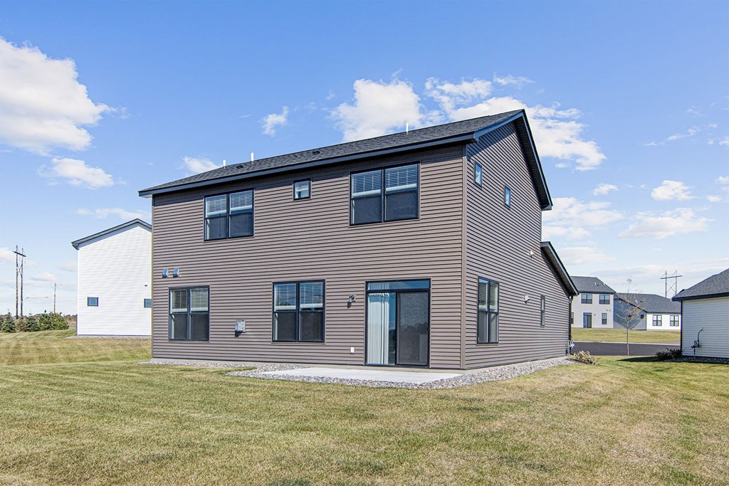 the back of the house with a lawn and blue sky in the background