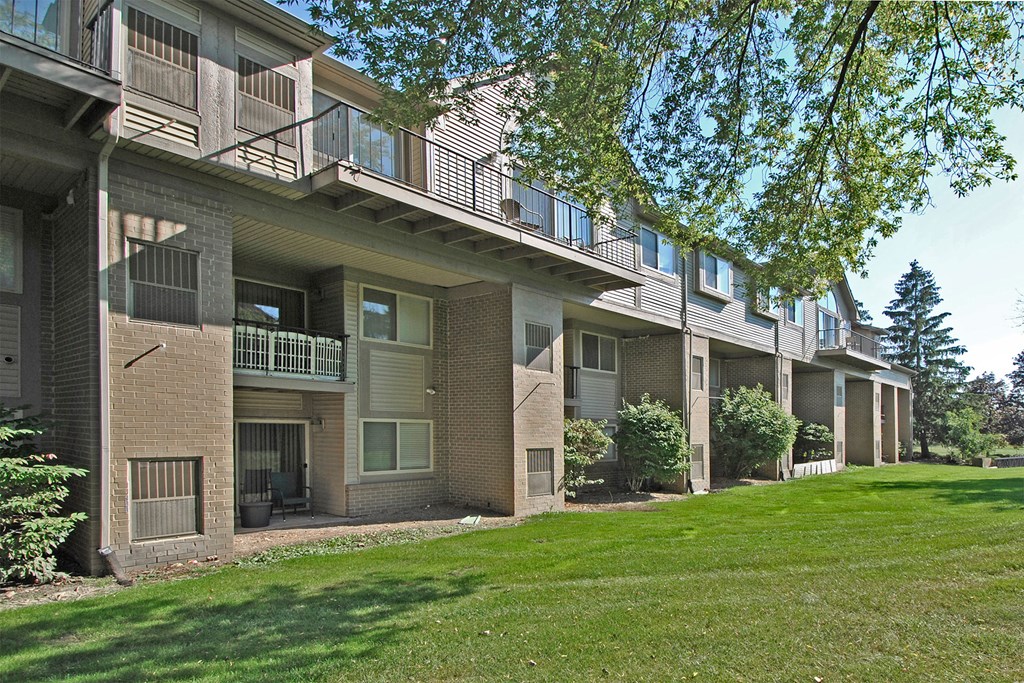 an exterior view of an apartment building with green grass and trees
