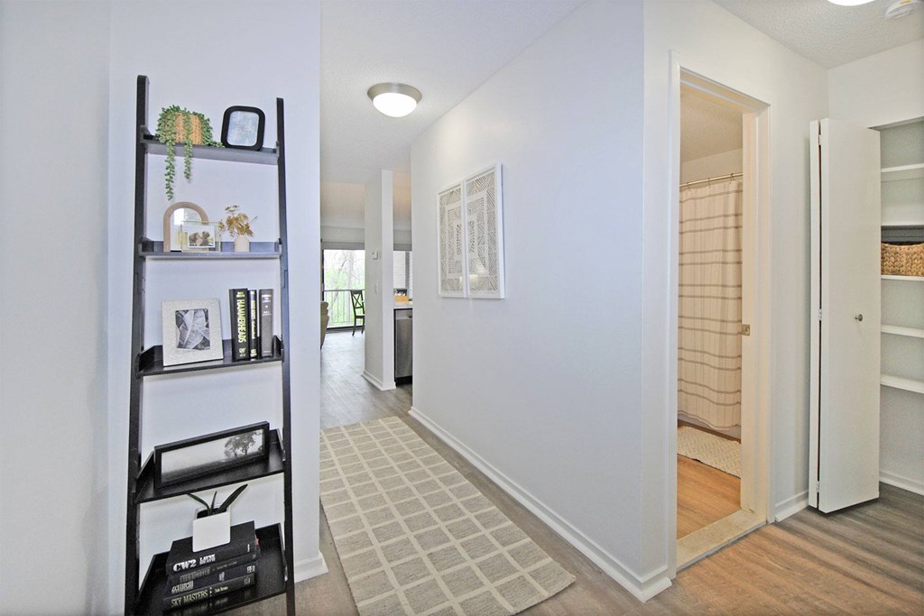 A hallway with a shelf on the left and a door on the right.