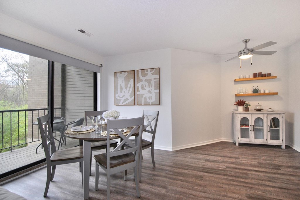 A dining room with a table set for two and a ceiling fan.
