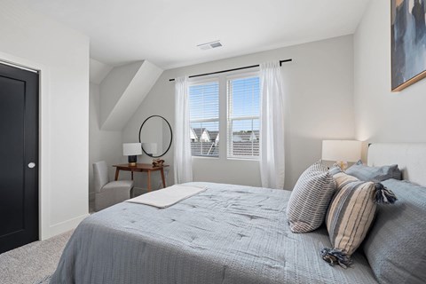 A bedroom with a large bed and a view of the outside through the window.