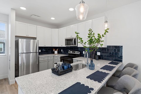 A kitchen with a white countertop and grey chairs.