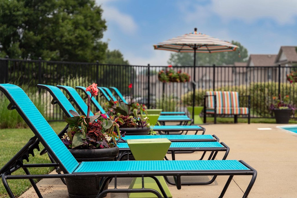 an outdoor patio with blue tables and chairs and an umbrella