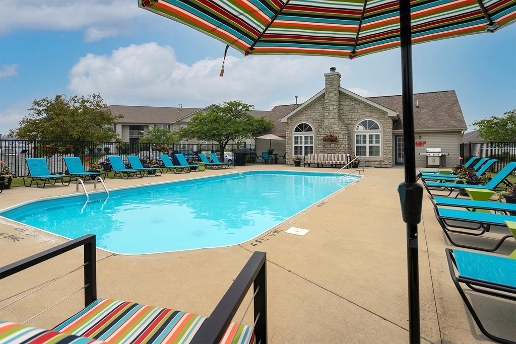 our resort style swimming pool is surrounded by lounge chairs and umbrellas