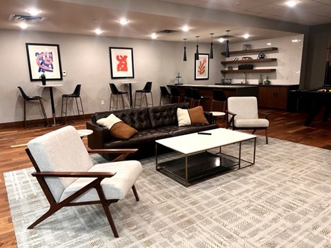 A living room with a black couch, a white chair, and a coffee table.