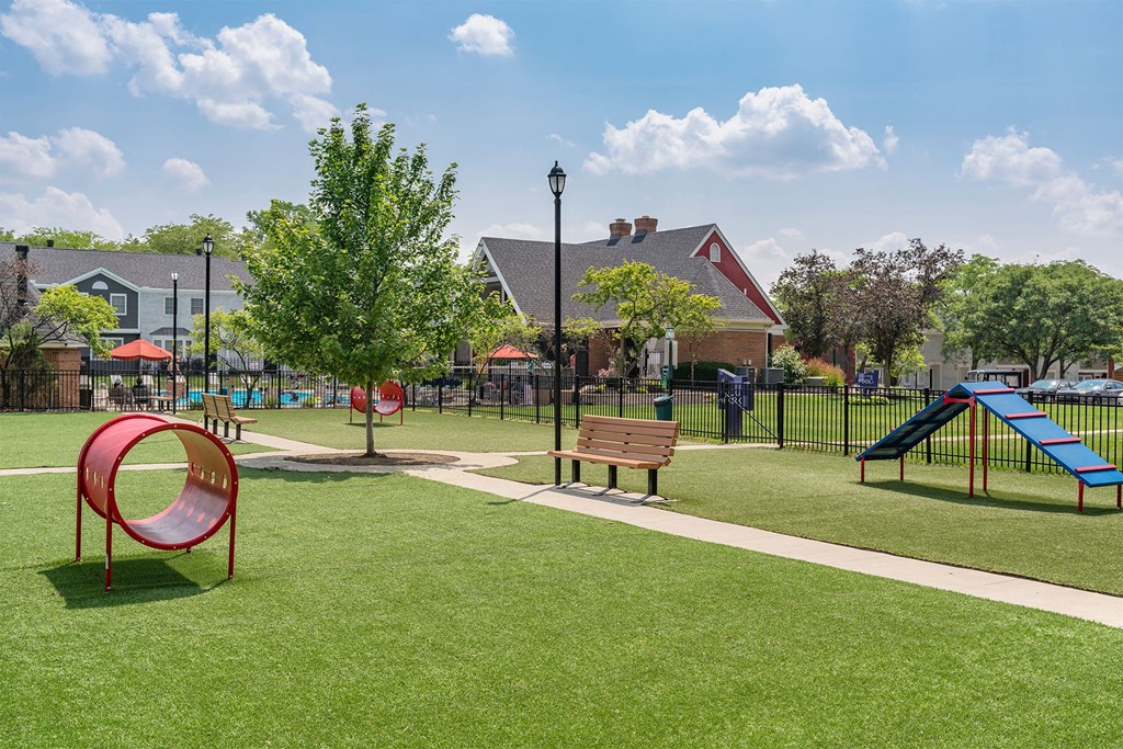 a playground with a swing set and a slide in a park with houses in the background