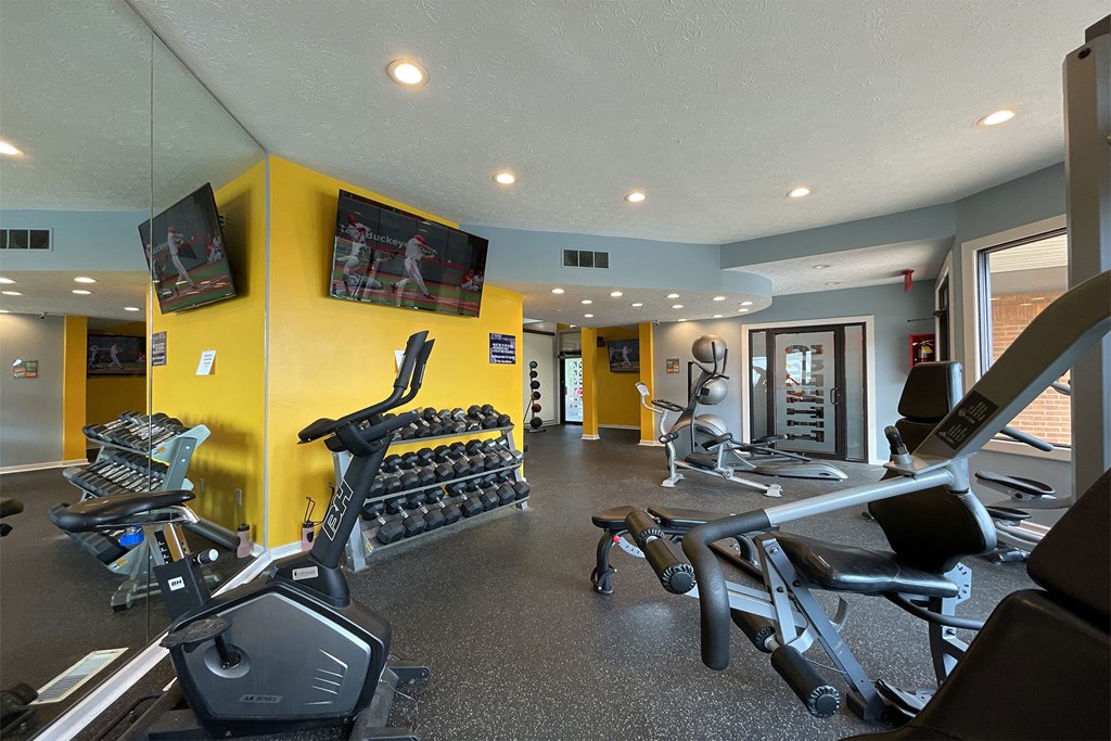 a gym with cardio equipment and a flat screen tv