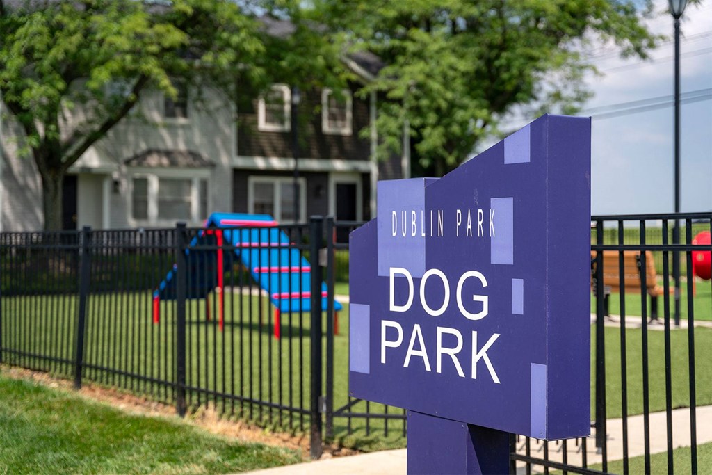 a purple sign that says dog park in front of a playground