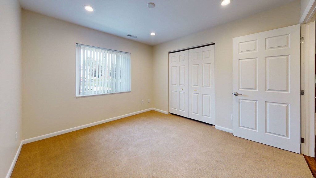 a bedroom with two closets and a window and two doors