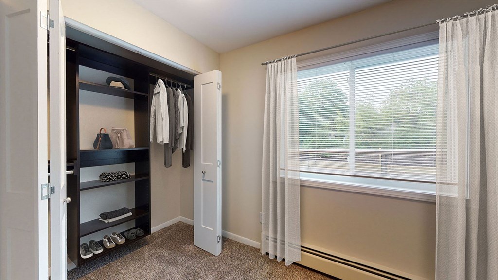 a closet in a bedroom with a window and a closet door