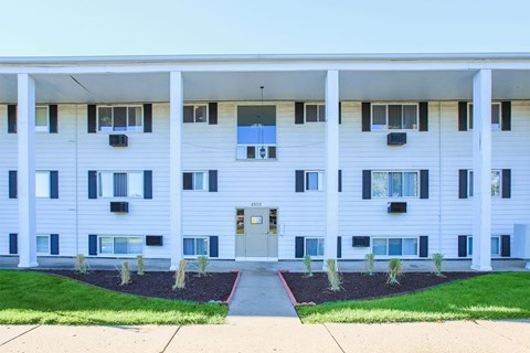 a white apartment building with a sidewalk and grass