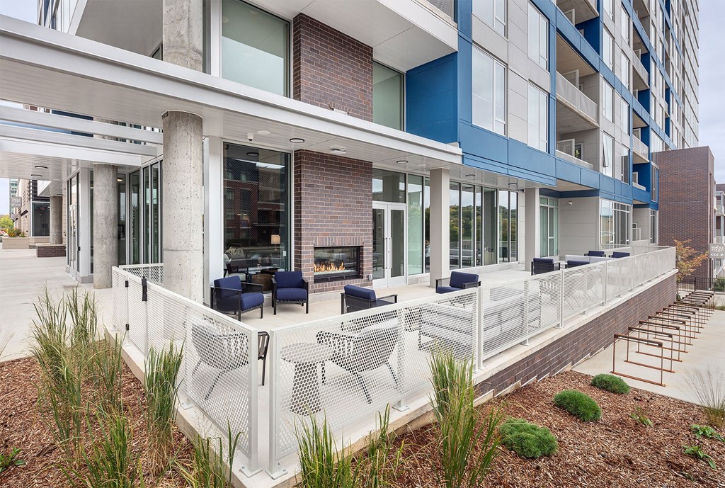an outdoor patio with chairs and a fireplace at an apartment building