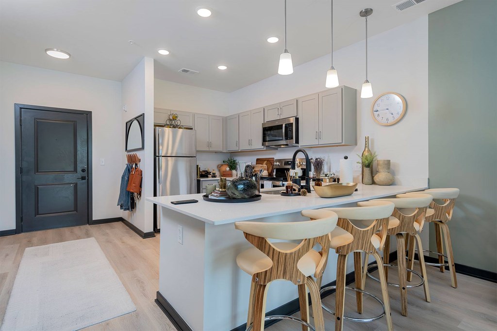 A kitchen with a white island and wooden bar stools.