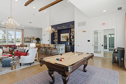 A pool table in a room with a red couch and a chandelier.