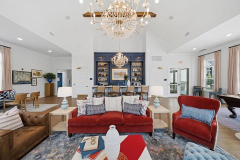 A living room with a red couch and a chandelier.