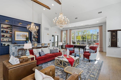 A living room with a red couch and a chandelier.