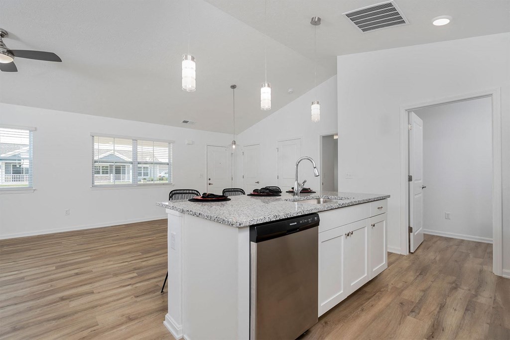 a kitchen and living room with white walls and wood floors