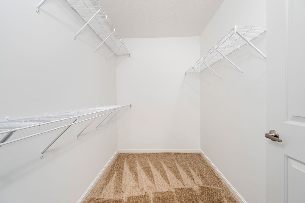 a walk in closet with white walls and white shelves