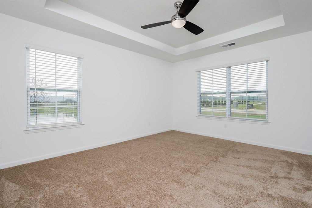 a bedroom with two windows and a ceiling fan