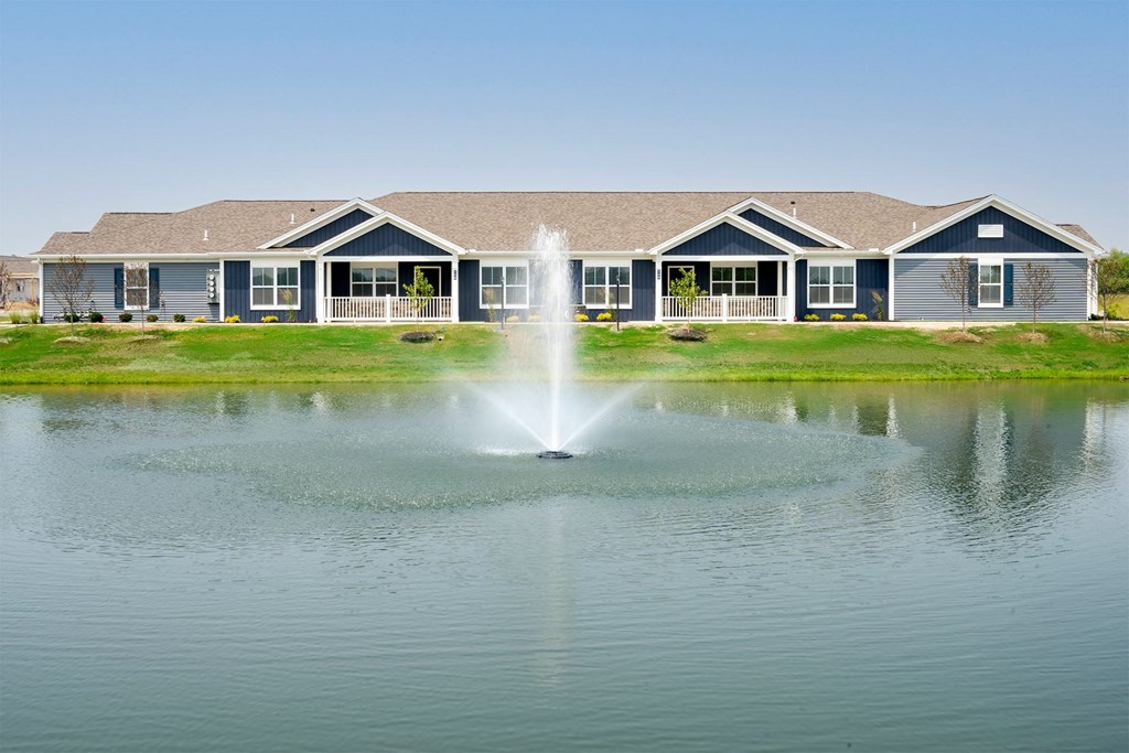 a fountain in a pond in front of a house