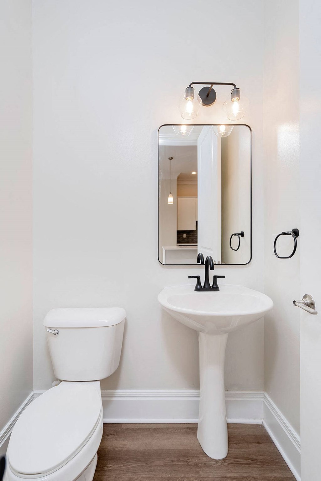 a bathroom with white walls and a white toilet next to a sink with a mirror above it