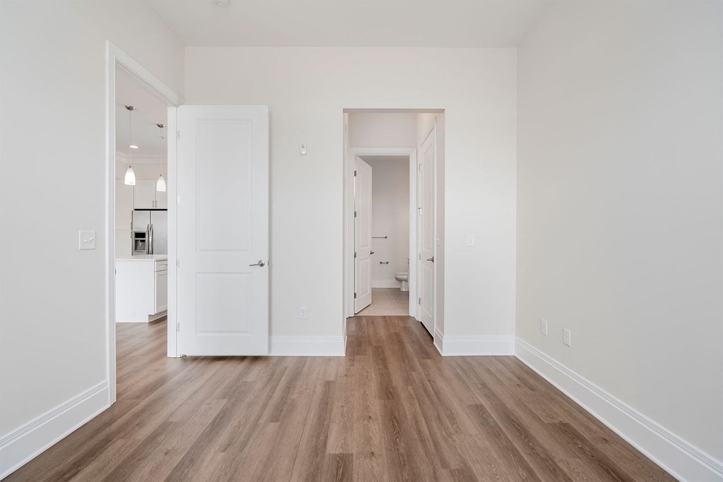 a bedroom with hardwood floors and white walls