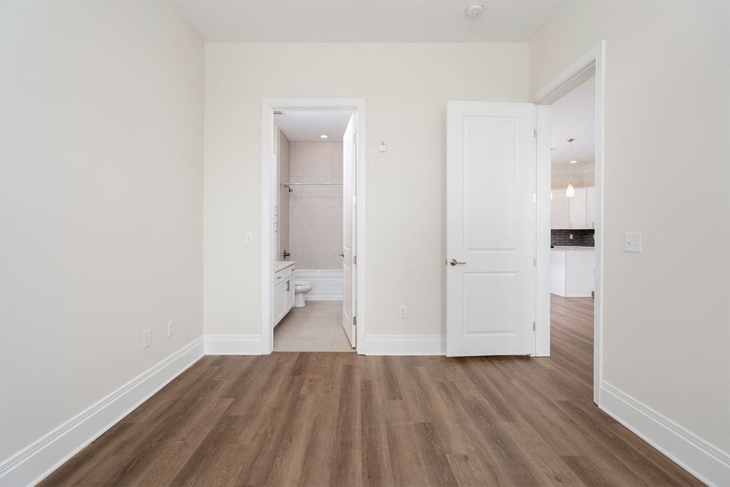 a bedroom with white walls and hardwood floors