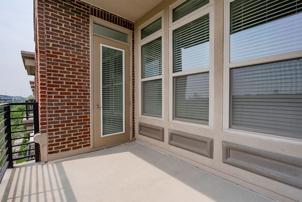 a balcony with a door and a brick wall
