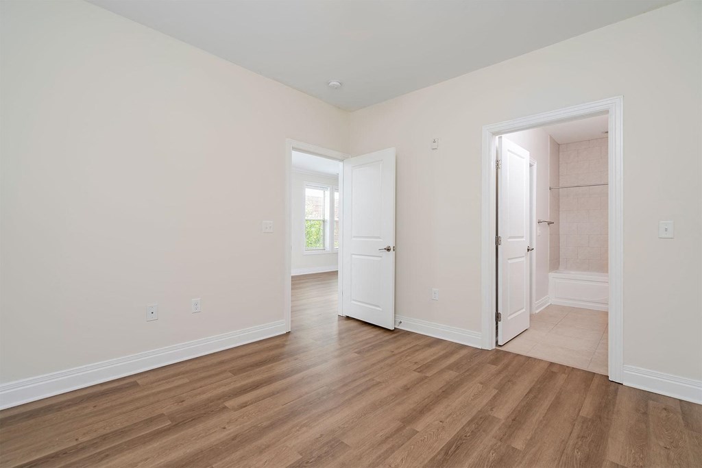 a bedroom with hardwood floors and white walls