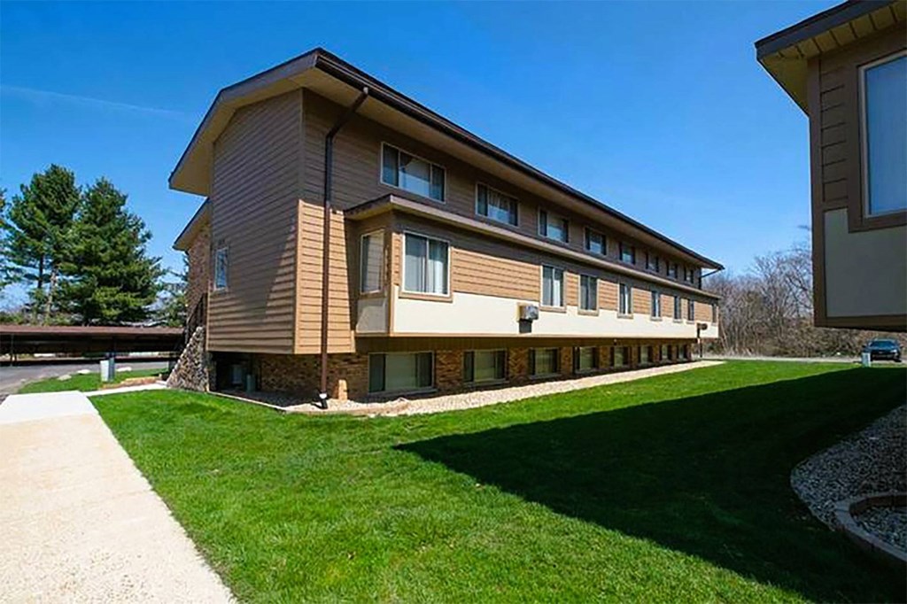 a large building with a green lawn and a sidewalk