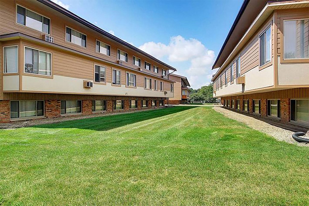 a row of apartment buildings with a grass yard