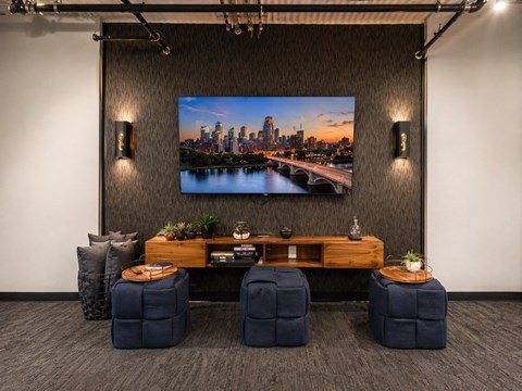 A modern room with a large screen displaying a cityscape and comfortable seating.
