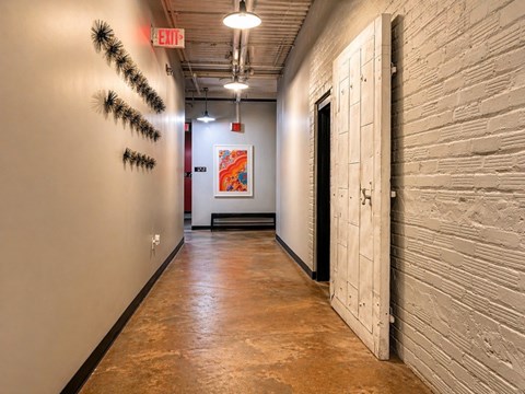 A hallway with a white door and a red exit sign on the wall.