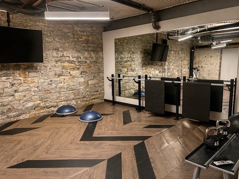 A gym with a wooden floor and a stone wall.