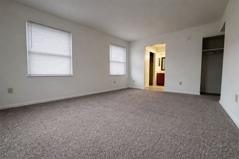 A room with carpeted floor and two windows.