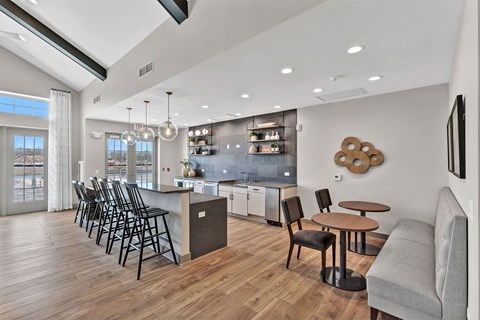 a living room with a kitchen and a bar with chairs