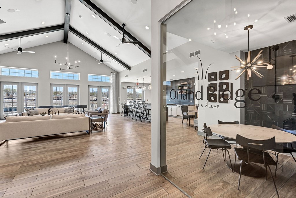 a communal area with tables and chairs and a large glass wall with a logo