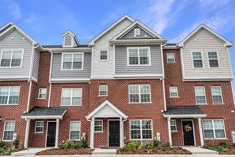 a red brick house with white siding and black doors
