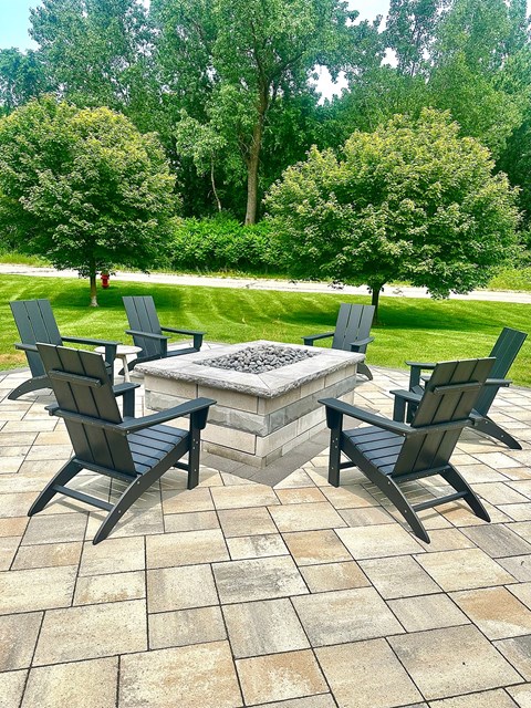 Four chairs are arranged around a table in a backyard.