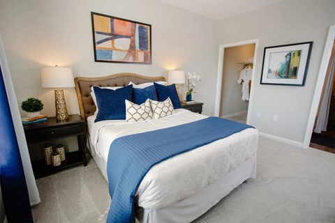 A bedroom with a large bed and a painting on the wall.