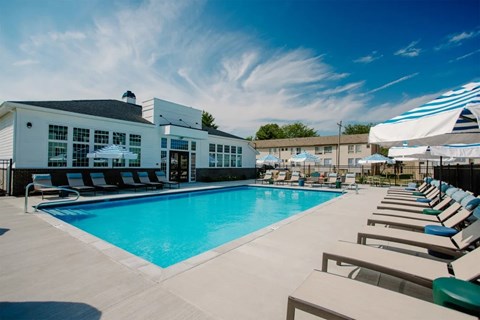 A large swimming pool area with sun loungers and a building in the background.