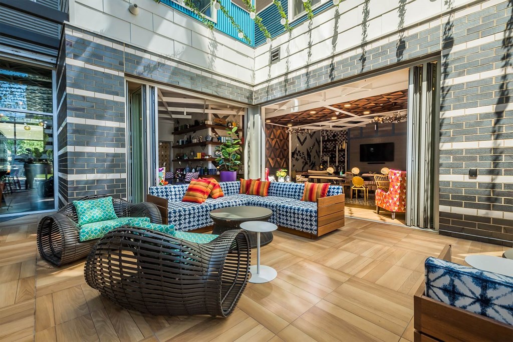 A modern outdoor seating area with wicker chairs and colorful cushions.