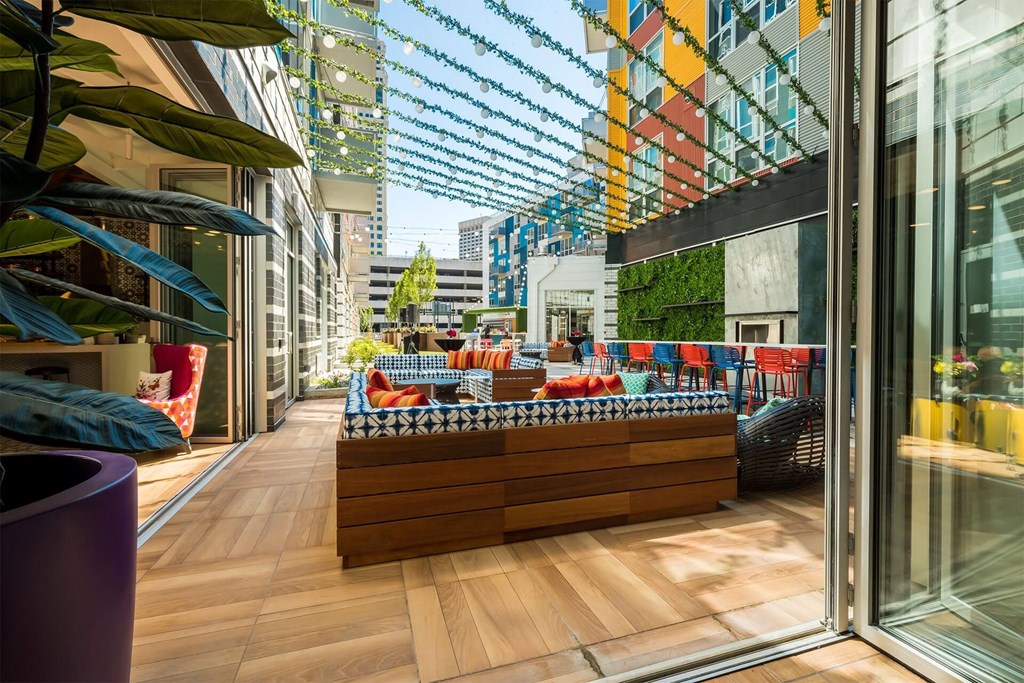 A modern outdoor seating area with a wooden bench and red chairs.