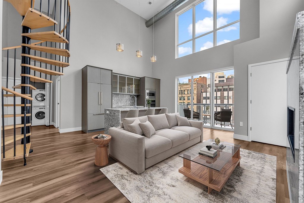 A modern living room with a spiral staircase and a large window.